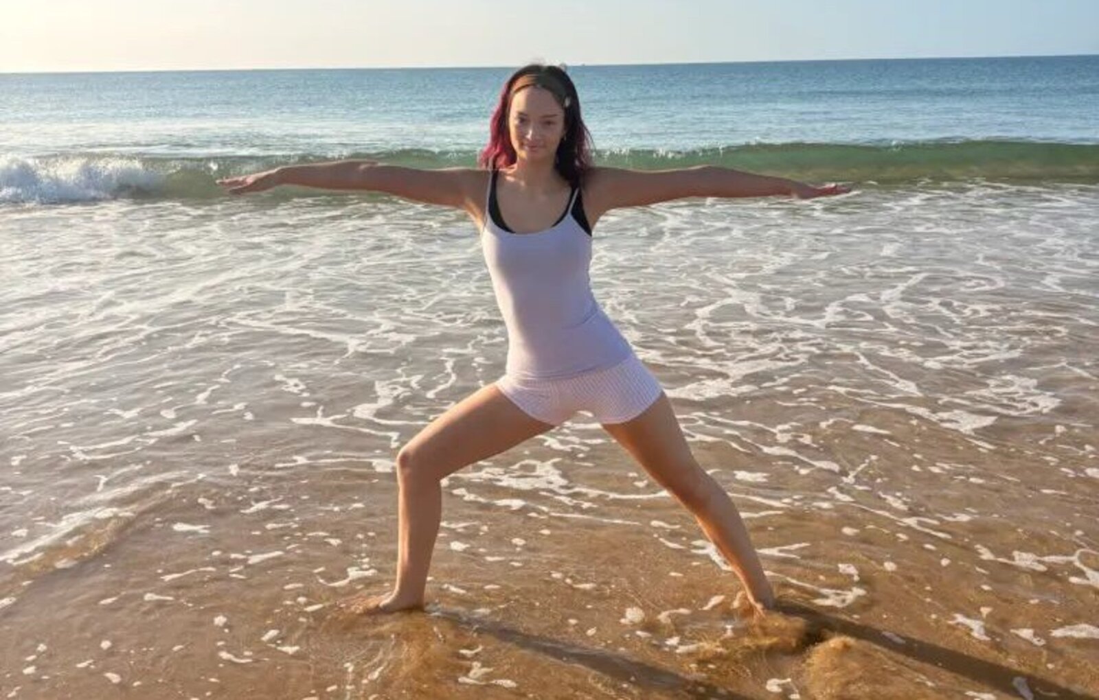 Kali practising a warrior yoga pose on the shoreline